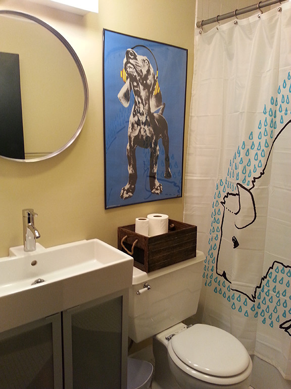 Inspiration för ett litet eklektiskt badrum, med luckor med glaspanel, vita skåp, en dusch/badkar-kombination, en toalettstol med separat cisternkåpa, gula väggar och ett avlångt handfat