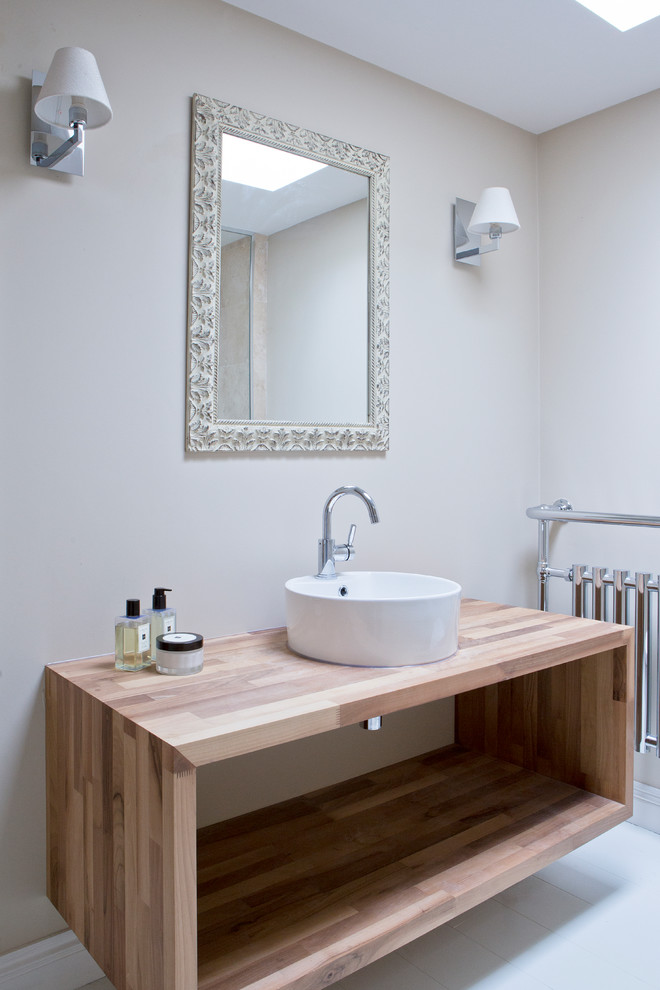 Inspiration for a transitional 3/4 beige tile white floor bathroom remodel in Wiltshire with open cabinets, light wood cabinets, beige walls, a vessel sink, wood countertops and beige countertops