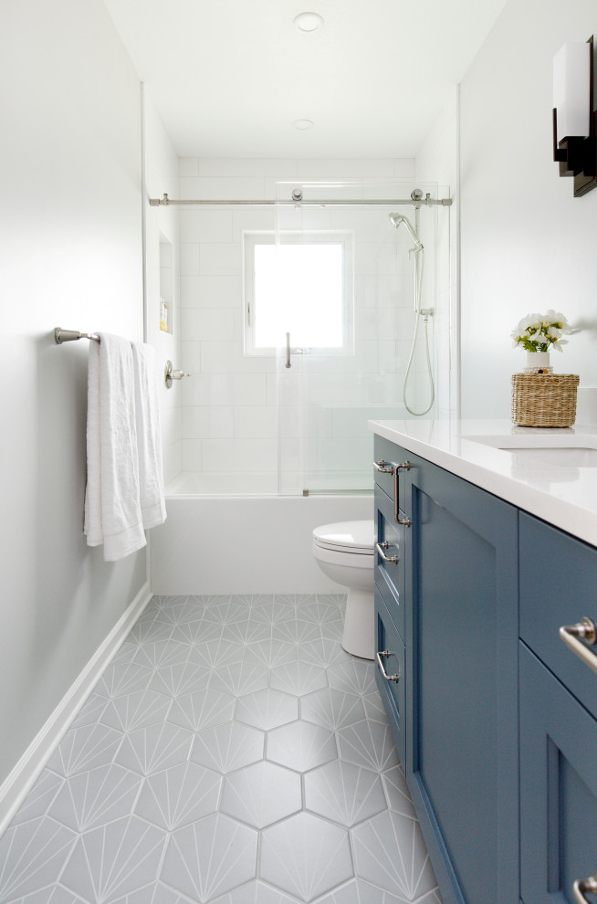 Стильный дизайн: ванная комната среднего размера в стиле неоклассика (современная классика) с фасадами с утопленной филенкой, синими фасадами, ванной в нише, душем в нише, раздельным унитазом, белой плиткой, керамической плиткой, серыми стенами, полом из керамогранита, врезной раковиной, столешницей из искусственного кварца, серым полом, душем с раздвижными дверями, белой столешницей, нишей, тумбой под одну раковину, встроенной тумбой и душевой кабиной - последний тренд