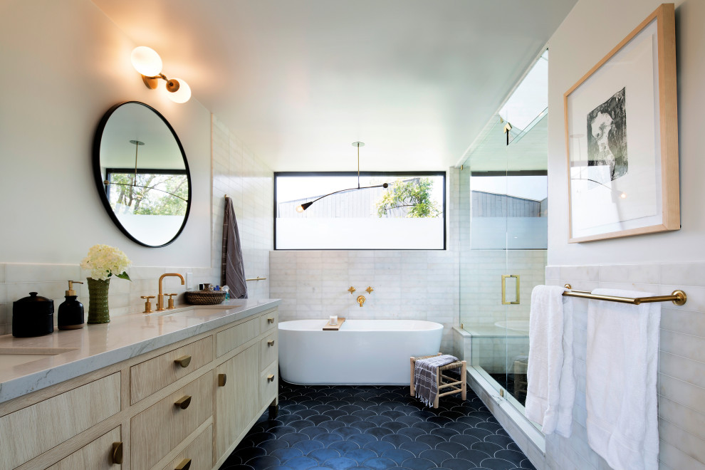 Пример оригинального дизайна: главная ванная комната среднего размера в современном стиле с фасадами с утопленной филенкой, светлыми деревянными фасадами, отдельно стоящей ванной, открытым душем, унитазом-моноблоком, белой плиткой, мраморной плиткой, белыми стенами, полом из цементной плитки, врезной раковиной, мраморной столешницей, черным полом, душем с распашными дверями, белой столешницей, сиденьем для душа, тумбой под две раковины и напольной тумбой