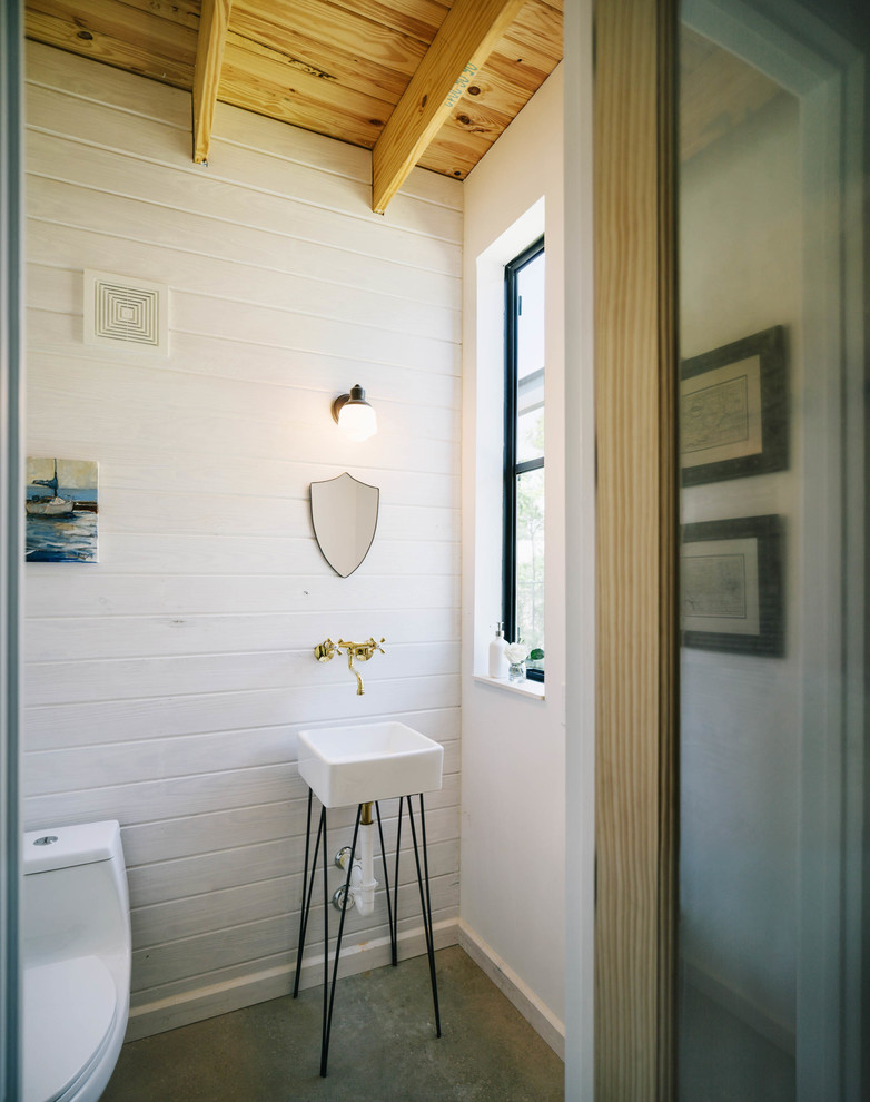 На фото: ванная комната в стиле лофт с консольной раковиной, унитазом-моноблоком, белыми стенами и бетонным полом с