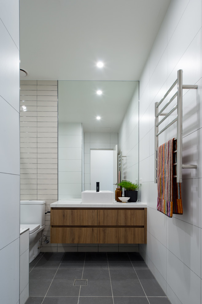 Exempel på ett mellanstort modernt badrum med dusch, med vit kakel, porslinskakel, vita väggar, klinkergolv i porslin, ett fristående handfat, bänkskiva i kvarts, släta luckor, skåp i mörkt trä och en toalettstol med separat cisternkåpa