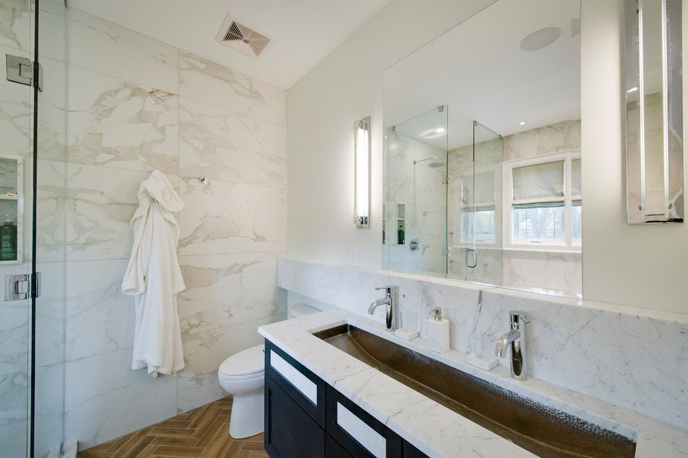 Photo of a medium sized modern ensuite bathroom with shaker cabinets, black cabinets, a freestanding bath, a corner shower, a one-piece toilet, granite worktops, beige tiles, white tiles, marble tiles, white walls, porcelain flooring, a trough sink, brown floors and a hinged door.