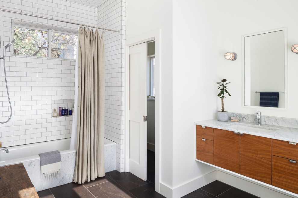 Inspiration for a medium sized scandinavian ensuite bathroom in Austin with medium wood cabinets, an alcove bath, a shower/bath combination, white tiles, metro tiles, white walls, ceramic flooring, a submerged sink, engineered stone worktops, brown floors and a shower curtain.