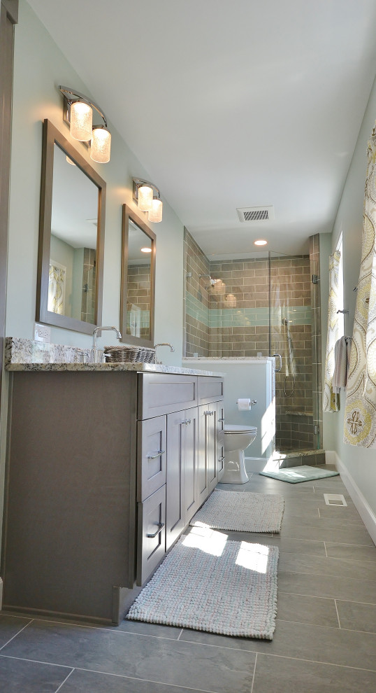 На фото: большая главная ванная комната в стиле неоклассика (современная классика) с фасадами с выступающей филенкой, коричневыми фасадами, угловым душем, унитазом-моноблоком, бежевой плиткой, керамической плиткой, бежевыми стенами, полом из ламината, врезной раковиной, столешницей из гранита, черным полом, душем с распашными дверями и разноцветной столешницей