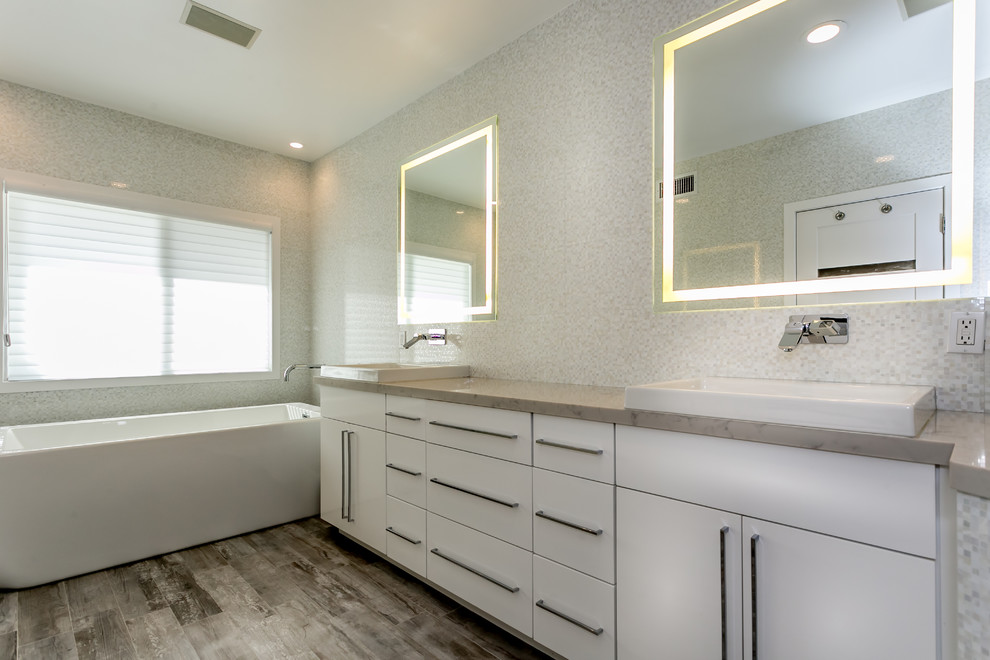Idéer för stora funkis en-suite badrum, med ett nedsänkt handfat, vita skåp, ett fristående badkar, en hörndusch, en vägghängd toalettstol, beige kakel, porslinskakel, vita väggar och klinkergolv i porslin