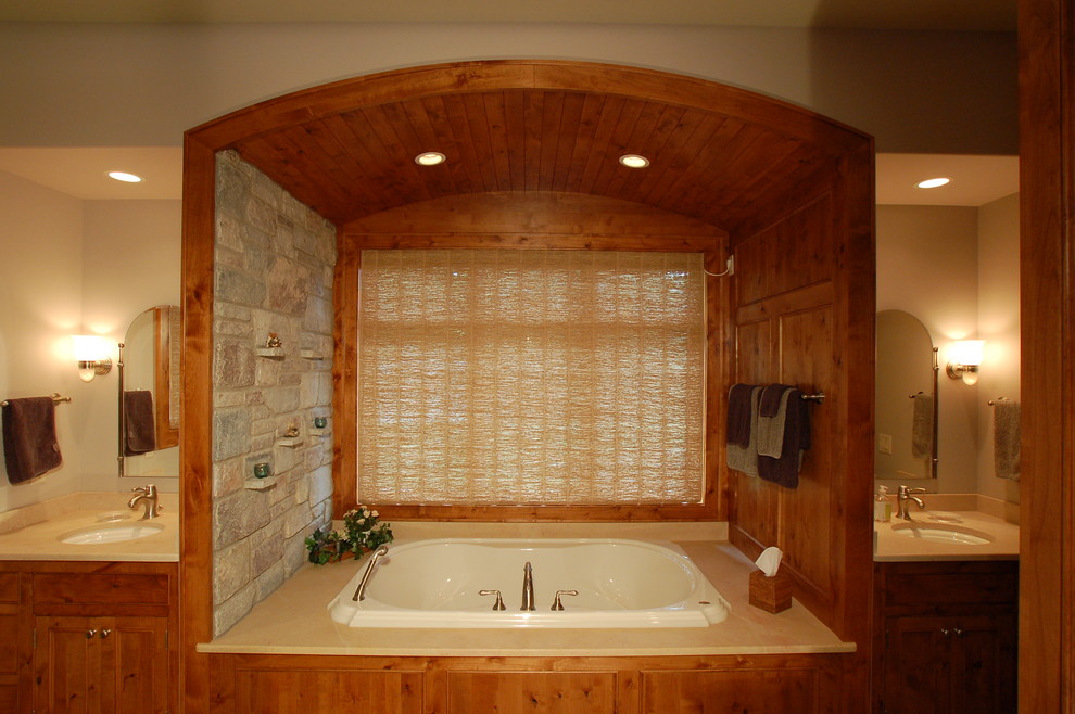 Immagine di un'ampia stanza da bagno padronale stile americano con lavabo sottopiano, ante con bugna sagomata, ante in legno scuro, vasca idromassaggio, piastrelle beige, piastrelle in ceramica e pareti beige