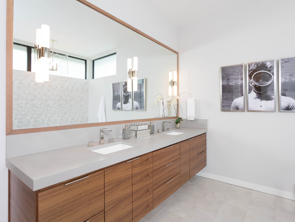 Example of a large minimalist master gray tile and porcelain tile concrete floor bathroom design in Austin with flat-panel cabinets, medium tone wood cabinets, a one-piece toilet, gray walls, an undermount sink and solid surface countertops