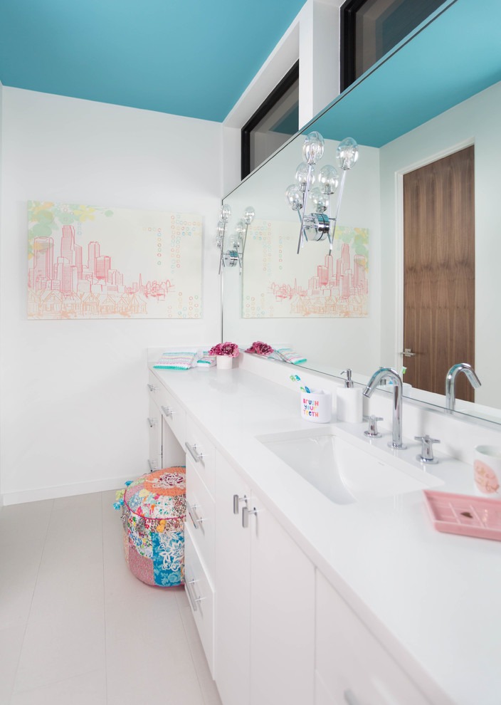 Idée de décoration pour une salle de bain minimaliste de taille moyenne pour enfant avec un placard à porte plane, des portes de placard blanches, une baignoire posée, un combiné douche/baignoire, WC à poser, un carrelage bleu, des carreaux de porcelaine, un mur blanc, un sol en carrelage de porcelaine, un lavabo encastré et un plan de toilette en surface solide.