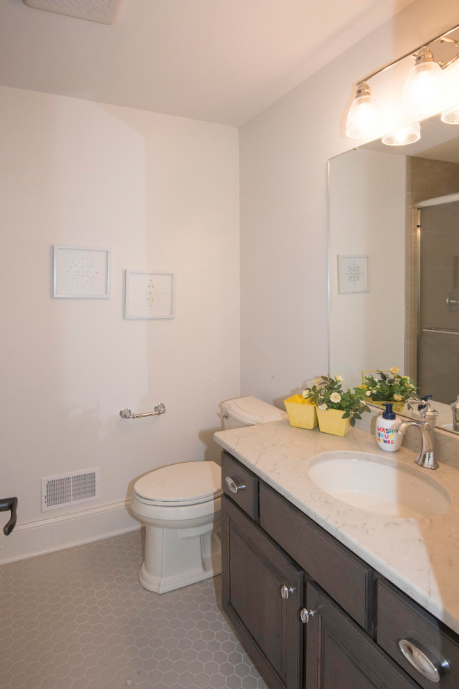 Mid-sized transitional 3/4 ceramic tile and gray floor bathroom photo in Milwaukee with a two-piece toilet, white walls, an undermount sink, quartz countertops, shaker cabinets, brown cabinets and gray countertops