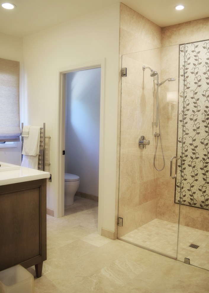 Large beach style ensuite bathroom in Santa Barbara with recessed-panel cabinets, medium wood cabinets, an alcove shower, a one-piece toilet, beige tiles, limestone tiles, white walls, travertine flooring, a submerged sink, marble worktops, beige floors and a hinged door.