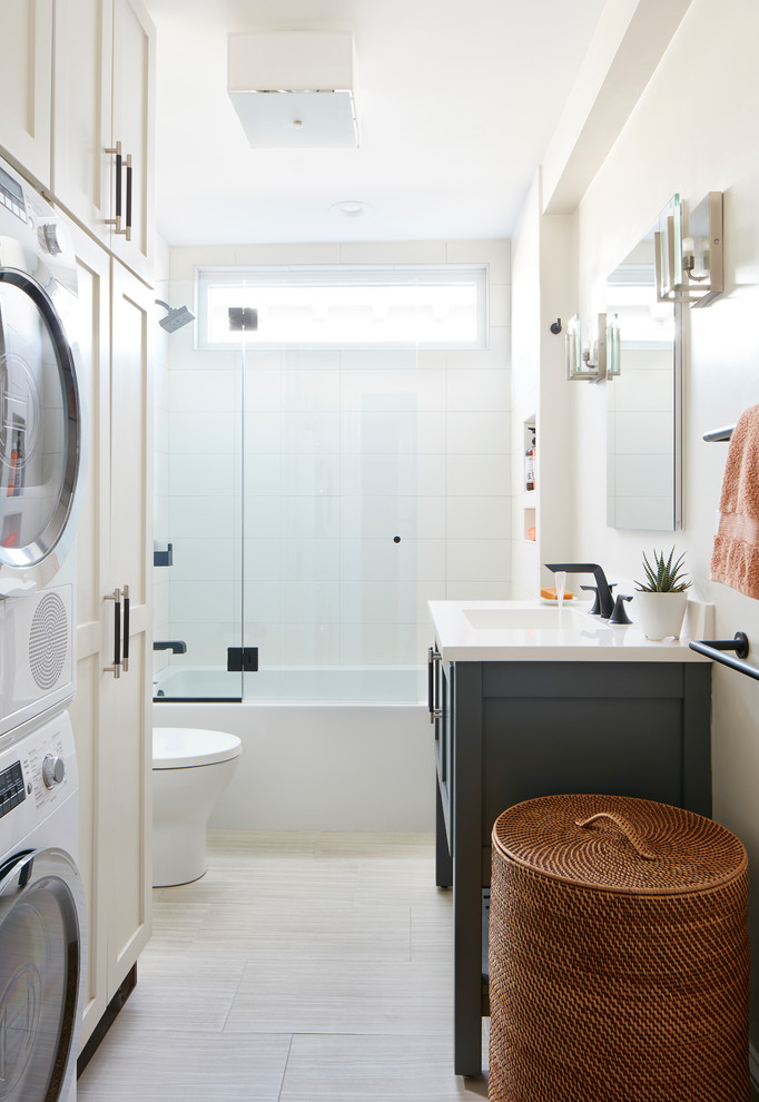 Modelo de cuarto de baño principal, contemporáneo, pequeño, con armarios estilo shaker, puertas de armario blancas, bañera encastrada, combinación de ducha y bañera, sanitario de dos piezas, baldosas y/o azulejos beige, baldosas y/o azulejos de porcelana, paredes blancas, suelo de baldosas de porcelana, lavabo tipo consola, suelo beige y tendedero