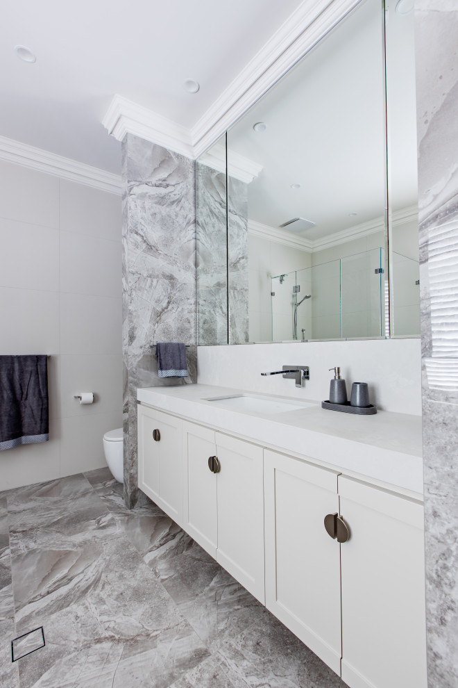 Inspiration for a traditional family bathroom in Adelaide with shaker cabinets, white cabinets, an alcove shower, a one-piece toilet, white tiles, porcelain tiles, white walls, porcelain flooring, a submerged sink, engineered stone worktops, grey floors, a hinged door and white worktops.