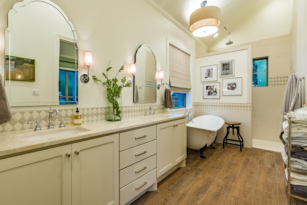 Example of a large cottage master beige tile dark wood floor and brown floor bathroom design in Austin with shaker cabinets, beige cabinets, beige walls, an undermount sink, granite countertops and beige countertops