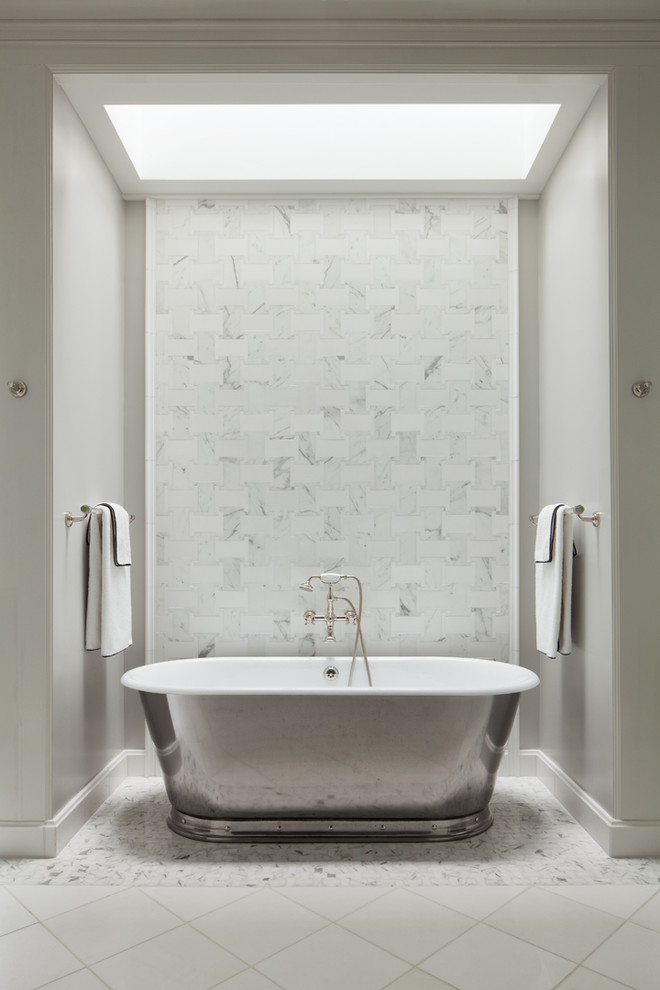 Cette photo montre une salle de bain principale chic avec une baignoire indépendante, un carrelage blanc, un carrelage de pierre, un mur gris et un sol en marbre.