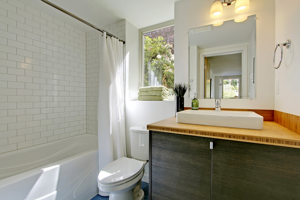 На фото: ванная комната в современном стиле с настольной раковиной, плиткой кабанчик и столешницей из дерева с