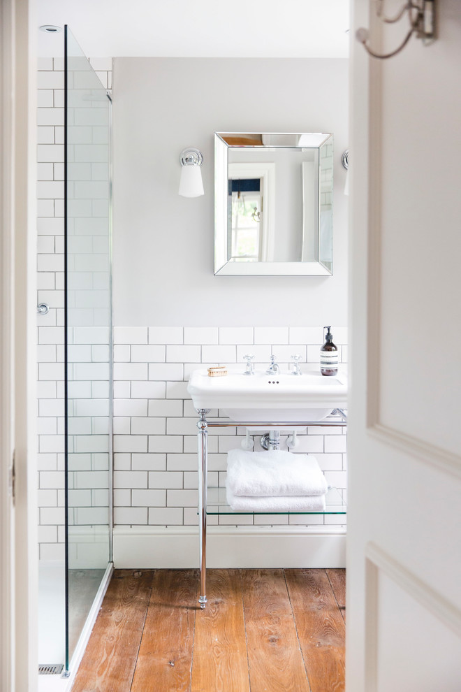Inspiration for a farmhouse bathroom in London with a corner shower, white tiles, metro tiles, grey walls, medium hardwood flooring, a wall-mounted sink, brown floors and an open shower.