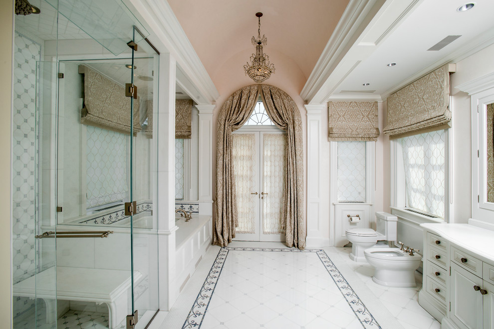 Пример оригинального дизайна: большая главная ванная комната в классическом стиле с белыми фасадами, полновстраиваемой ванной, душем в нише, белой плиткой, каменной плиткой, розовыми стенами, полом из керамической плитки, мраморной столешницей, фасадами с утопленной филенкой, биде, душем с распашными дверями, врезной раковиной, белым полом и белой столешницей