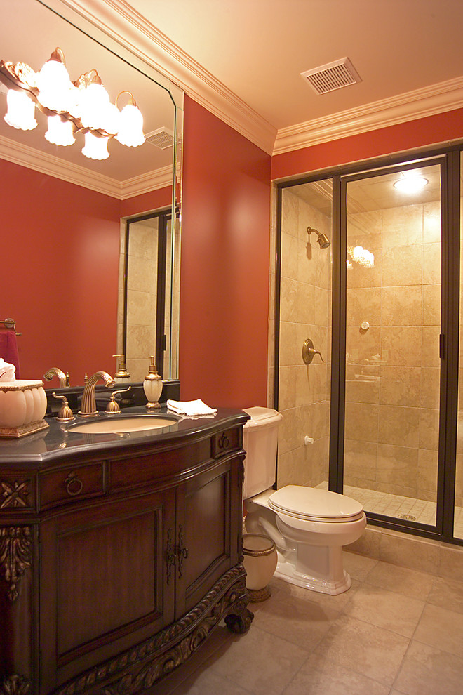 Klassisk inredning av ett stort badrum med dusch, med ett undermonterad handfat, möbel-liknande, skåp i mörkt trä, granitbänkskiva, ett platsbyggt badkar, en dusch i en alkov, en toalettstol med hel cisternkåpa, röda väggar och travertin golv