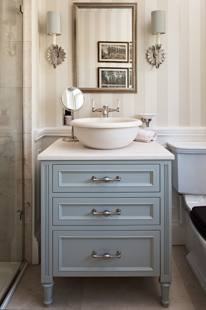 Klassisk inredning av ett beige beige badrum, med blå skåp, beige väggar, ett fristående handfat, beiget golv och luckor med infälld panel