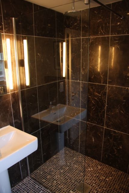 Idee per una piccola stanza da bagno con doccia classica con doccia aperta, piastrelle marroni, lastra di pietra, pareti marroni, pavimento in marmo e lavabo a colonna