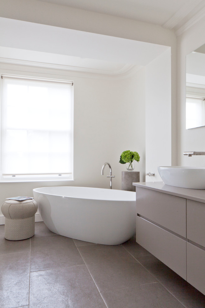 Contemporary ensuite bathroom in London with flat-panel cabinets, grey cabinets, a freestanding bath, white walls and a vessel sink.