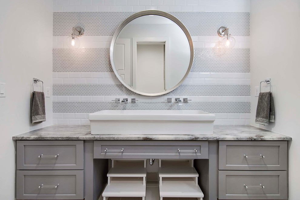 Cette photo montre une grande salle de bain bord de mer pour enfant avec un placard à porte shaker, des portes de placard grises, un carrelage gris, des carreaux de porcelaine, un plan de toilette en marbre, un mur blanc, une vasque et un plan de toilette gris.