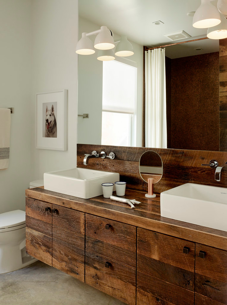 Inspiration pour une salle de bain design en bois foncé avec une vasque, un placard à porte plane et un plan de toilette en bois.
