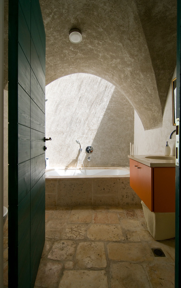 Inspiration pour une douche en alcôve principale méditerranéenne avec un lavabo intégré, un placard à porte plane, des portes de placard oranges, une baignoire encastrée, un carrelage beige, un mur beige et un sol en ardoise.
