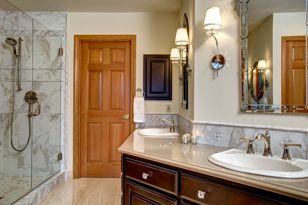 Example of a large tuscan master beige tile and porcelain tile limestone floor bathroom design in Seattle with a drop-in sink, raised-panel cabinets, dark wood cabinets, quartz countertops, a one-piece toilet and beige walls
