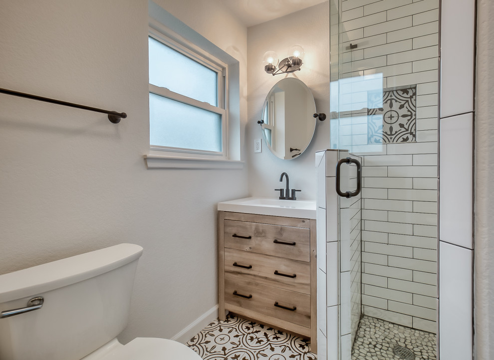 Classic ensuite bathroom in Dallas with flat-panel cabinets, medium wood cabinets, a corner shower, grey tiles, white tiles, white walls, an integrated sink, multi-coloured floors, a hinged door, white worktops, a single sink and a built in vanity unit.