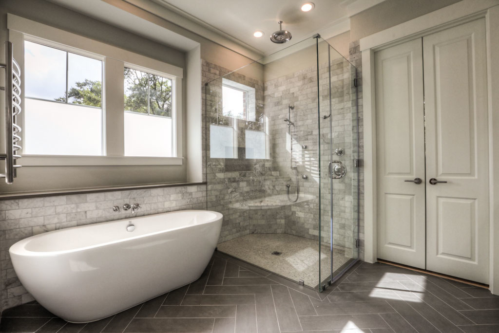 This is an example of a large traditional ensuite bathroom in Houston with a freestanding bath, a corner shower, white tiles, marble tiles, beige walls, laminate floors, grey floors and a hinged door.