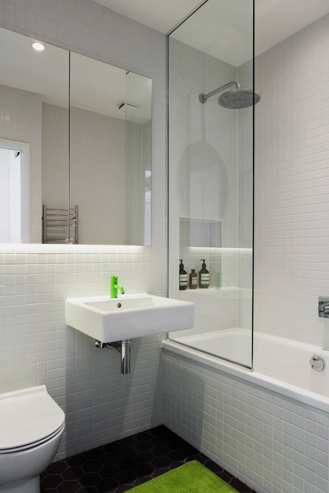 Exemple d'une petite salle de bain scandinave avec une baignoire posée, un carrelage blanc, des carreaux de céramique, un mur blanc, carreaux de ciment au sol, un lavabo suspendu, un sol noir, aucune cabine, un combiné douche/baignoire et WC suspendus.