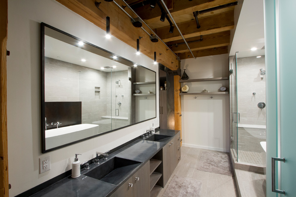 Cette image montre une petite salle de bain principale urbaine avec une baignoire indépendante, WC à poser, un carrelage gris, un plan de toilette en béton, une cabine de douche à porte battante et un plan de toilette gris.
