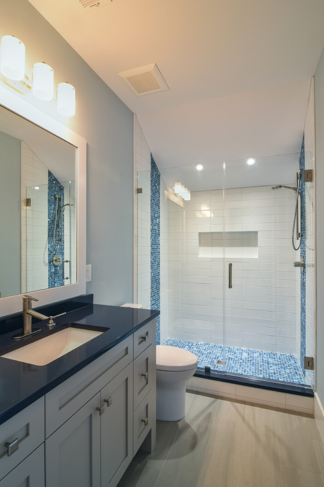 Foto på ett mellanstort vintage blå badrum med dusch, med skåp i shakerstil, blå skåp, en dusch i en alkov, en toalettstol med separat cisternkåpa, blå kakel, mosaik, blå väggar, klinkergolv i porslin, ett undermonterad handfat, bänkskiva i akrylsten och dusch med gångjärnsdörr