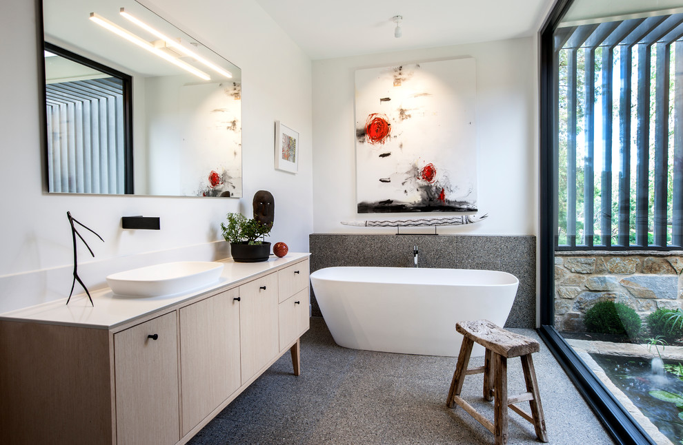 Modern inredning av ett stort en-suite badrum, med ett fristående badkar, en hörndusch, en vägghängd toalettstol, vita väggar, terrazzogolv, ett integrerad handfat, bänkskiva i akrylsten och med dusch som är öppen