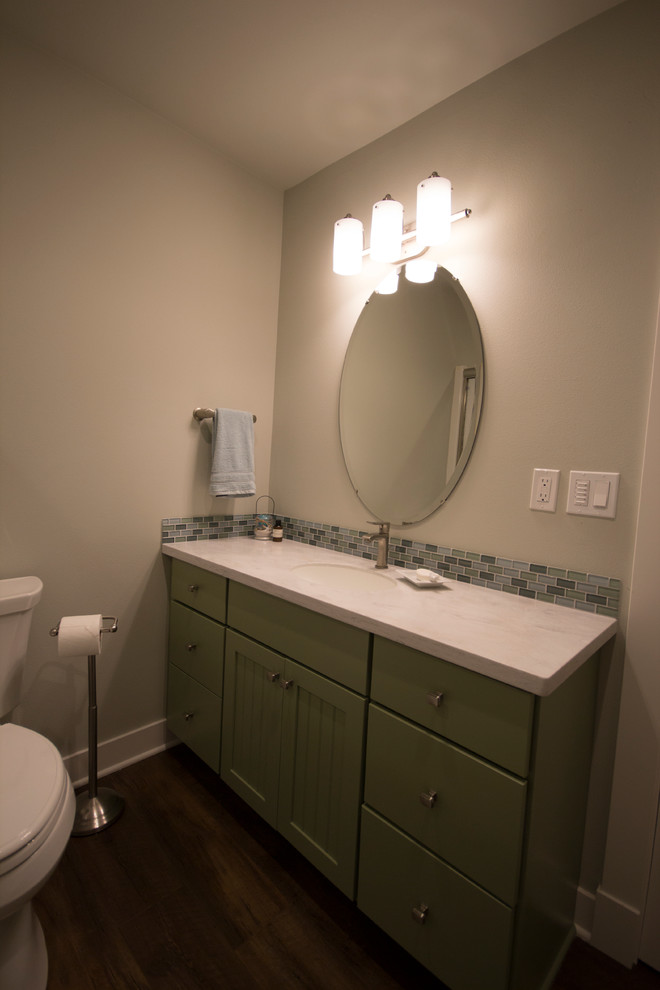Exempel på ett mellanstort maritimt badrum med dusch, med luckor med infälld panel, gröna skåp, en dusch i en alkov, en toalettstol med separat cisternkåpa, flerfärgad kakel, glaskakel, grå väggar, vinylgolv, ett integrerad handfat och bänkskiva i akrylsten