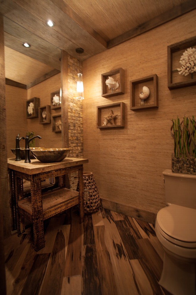 Example of a mid-sized mountain style dark wood floor and brown floor powder room design in Orange County with a vessel sink, a one-piece toilet and beige walls