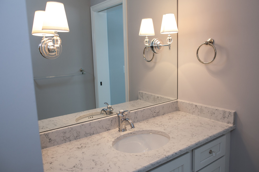 Aménagement d'une salle de bain craftsman avec un placard à porte shaker, des portes de placard blanches, un mur gris, un lavabo encastré, un plan de toilette en granite et un plan de toilette gris.
