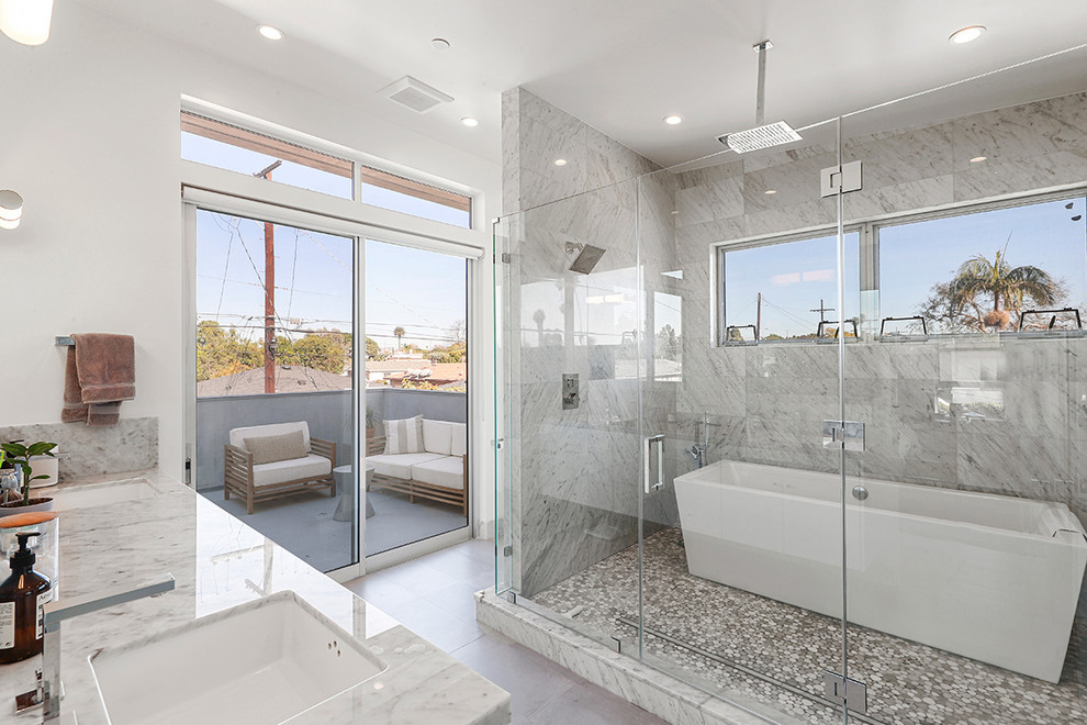 Bild på ett litet funkis badrum, med ett fristående badkar, våtrum, vita väggar, ett undermonterad handfat, marmorbänkskiva, grått golv och dusch med gångjärnsdörr