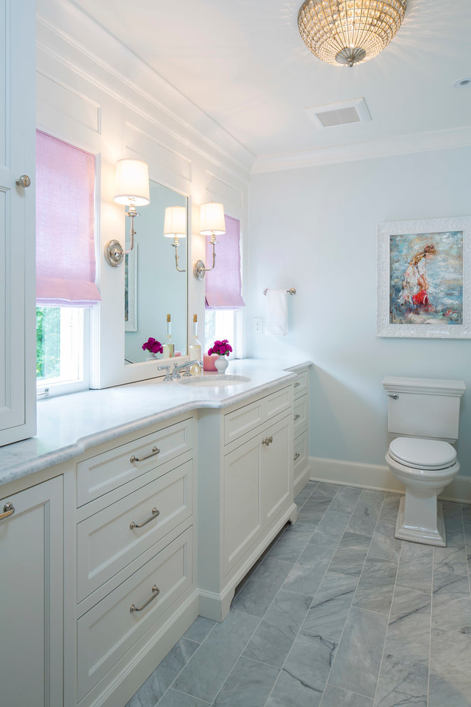 Aménagement d'une salle de bain classique avec un placard à porte shaker, des portes de placard blanches, WC séparés, un mur bleu, un lavabo encastré et un plan de toilette en marbre.