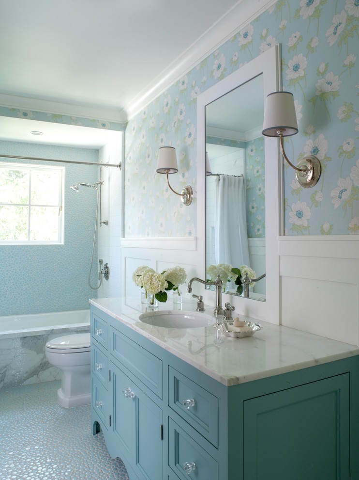 Идея дизайна: ванная комната среднего размера в классическом стиле с синими фасадами, полновстраиваемой ванной, синей плиткой, синими стенами, мраморной столешницей, врезной раковиной, фасадами с утопленной филенкой, душем над ванной, галечной плиткой, полом из галечной плитки, белой столешницей и окном