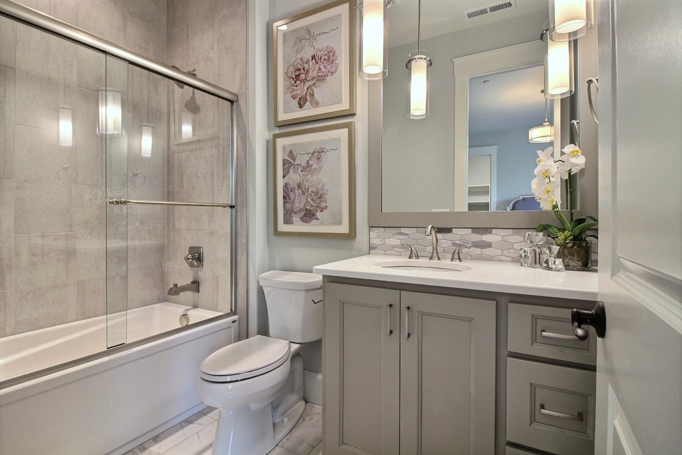 Idéer för att renovera ett stort amerikanskt vit vitt en-suite badrum, med luckor med infälld panel, grå skåp, ett badkar i en alkov, en dusch/badkar-kombination, en toalettstol med separat cisternkåpa, grå kakel, keramikplattor, grå väggar, klinkergolv i keramik, ett undermonterad handfat, bänkskiva i kvarts, grått golv och dusch med skjutdörr