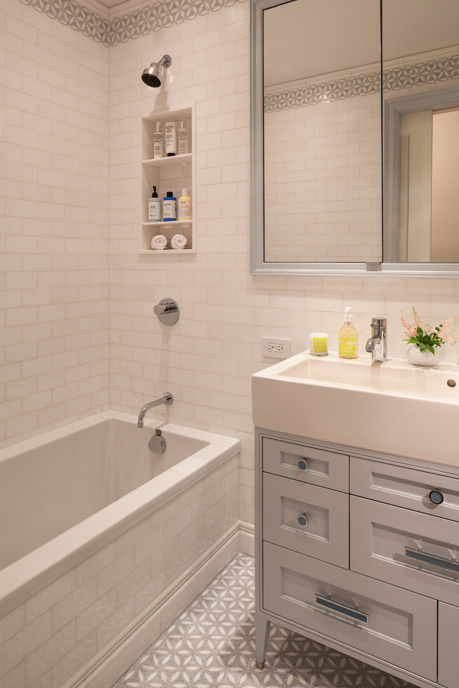 Bild på ett mellanstort vintage badrum för barn, med ett integrerad handfat, skåp i shakerstil, ett platsbyggt badkar, en dusch/badkar-kombination, en vägghängd toalettstol, blå kakel, mosaik, vita väggar, marmorgolv och grå skåp