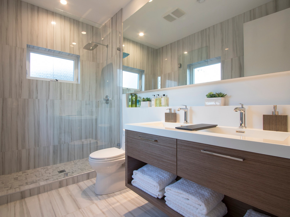 На фото: ванная комната в современном стиле с плоскими фасадами, фасадами цвета дерева среднего тона, открытым душем, унитазом-моноблоком, серой плиткой, белыми стенами, монолитной раковиной и открытым душем с