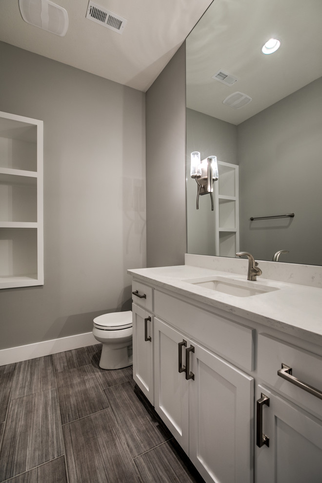 Idéer för att renovera ett mellanstort lantligt badrum med dusch, med skåp i shakerstil, en toalettstol med separat cisternkåpa, klinkergolv i porslin, grå skåp, ett fristående badkar, keramikplattor, grå väggar, ett nedsänkt handfat, bänkskiva i akrylsten och brunt golv