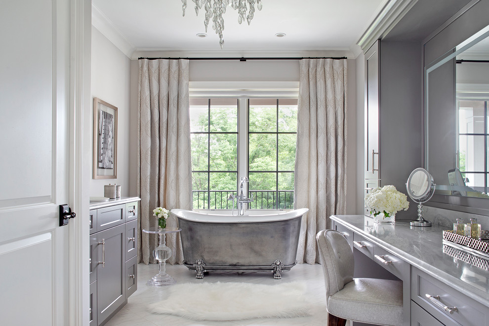 Inspiration pour une salle de bain principale traditionnelle avec un placard à porte shaker, des portes de placard grises, une baignoire sur pieds, un mur gris, un plan de toilette en marbre, un sol blanc et un plan de toilette gris.