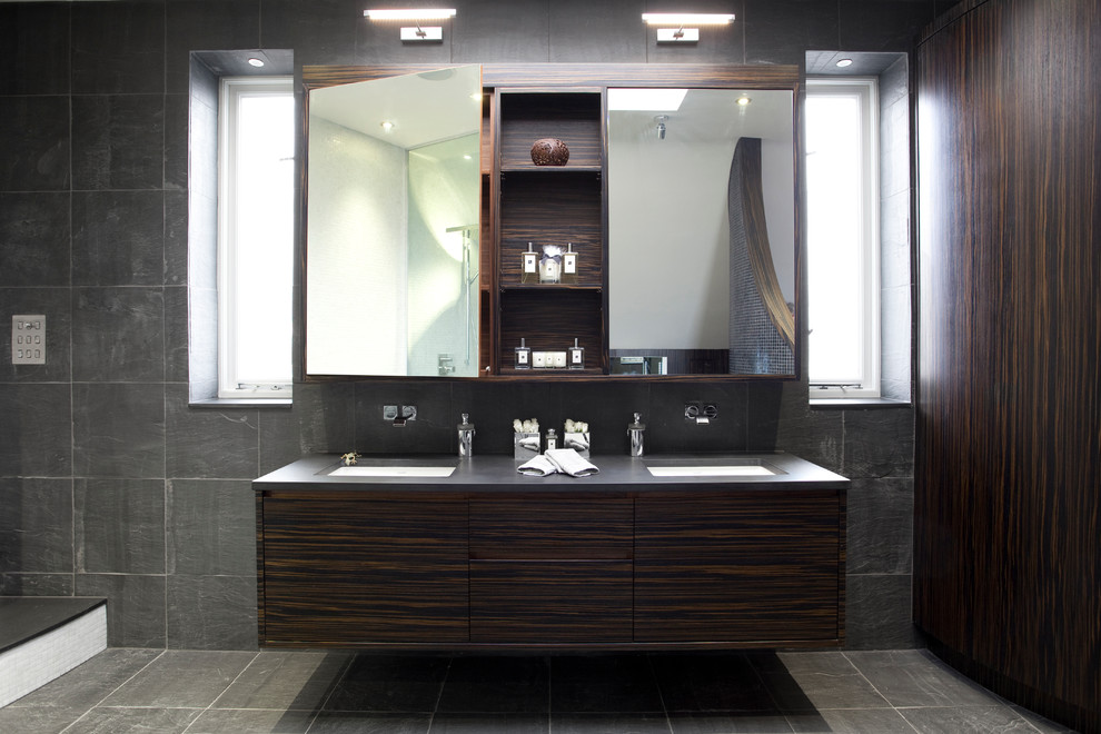 Exemple d'une salle de bain principale tendance en bois foncé avec un lavabo encastré, un placard à porte plane, un plan de toilette en bois, WC à poser, un carrelage gris, des carreaux de céramique, un mur blanc et un sol en carrelage de céramique.