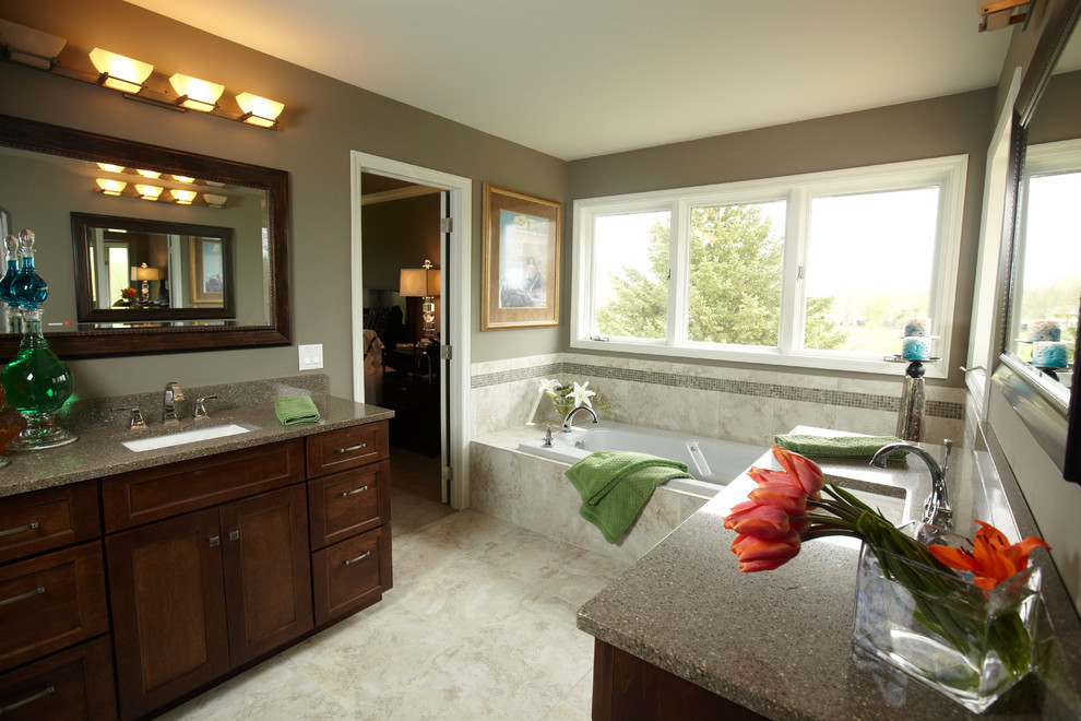 Modelo de cuarto de baño principal clásico con lavabo bajoencimera, armarios estilo shaker, puertas de armario de madera en tonos medios, bañera encastrada, baldosas y/o azulejos beige y paredes grises
