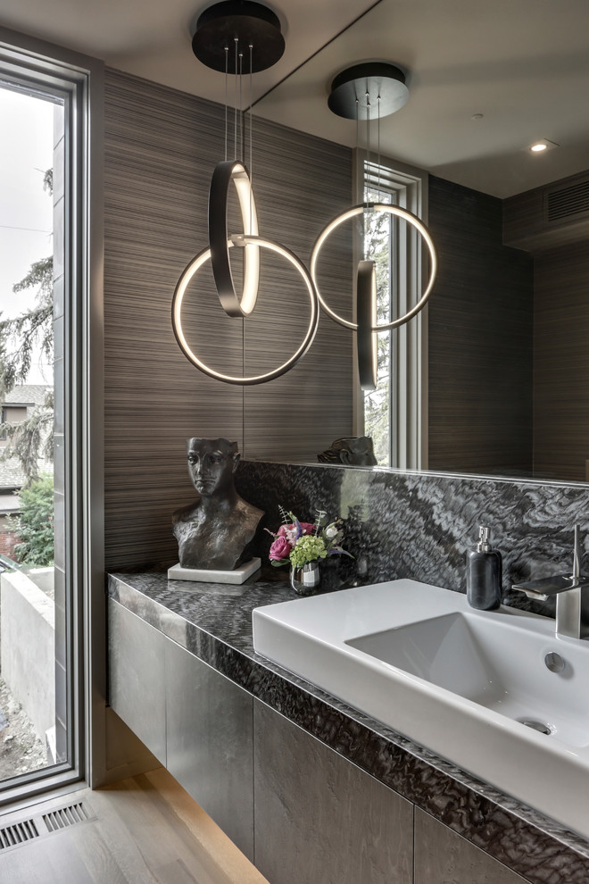 Diseño de cuarto de baño actual con armarios con paneles lisos, suelo de madera clara y encimeras multicolor